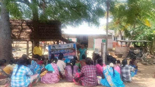 Community members seated outdoors at a village programme